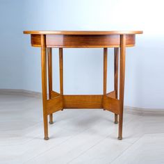 a wooden table sitting on top of a white floor next to a blue wall in an empty room