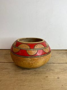 a bowl sitting on top of a wooden table next to a white wall and floor