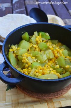 corn and green peppers in a pot on a cutting board next to tortilla shells