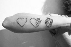 a woman's arm with three heart tattoos on it