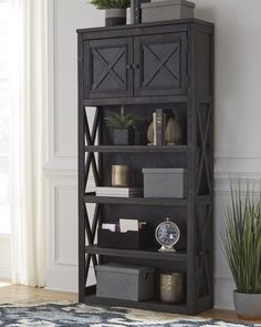 a black bookcase with plants and other items on it in front of a window