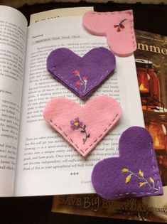 the book is open to show three felt heart pieces in different colors and sizes, each with flowers on them