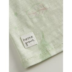 a close up of a label on a green and white shirt with leaves drawn on it