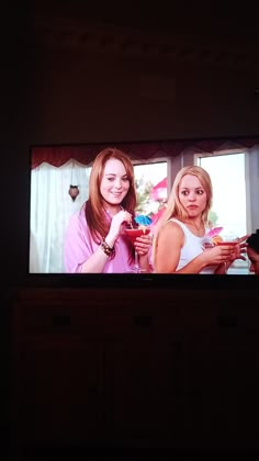 two women standing in front of a tv screen