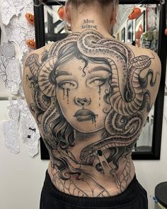 the back of a woman's body with a tattoo on her shoulder and head