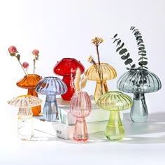 several different colored glass vases sitting on top of a white box with flowers in them