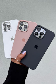 three iphones in different colors are being held up by someone's hand with their fingers