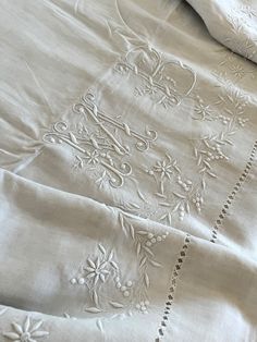 an embroidered bed spread with white linens on it