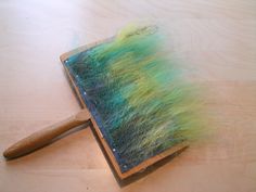 a brush with green and yellow hair on it sitting on top of a wooden table