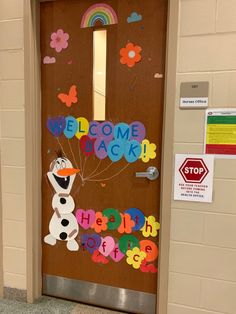 a door decorated with the words welcome back and a snowman holding a bunch of balloons