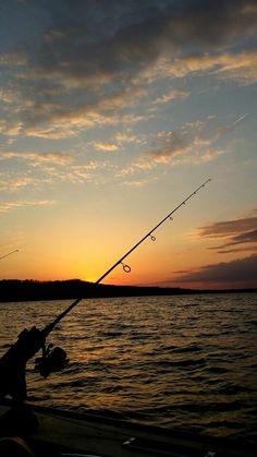 a man is fishing on the water at sunset