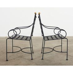 a pair of metal chairs sitting on top of a cement floor next to each other