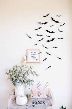 a table topped with vases filled with flowers next to a wall mounted flock of bats