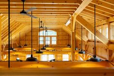 the inside of a large wooden building with several lights hanging from it's ceiling