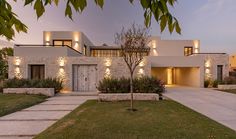 a modern house is lit up at night with lights on the front and side windows