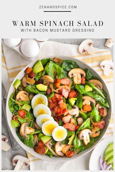 a salad with hard boiled eggs, spinach and bacon is shown in a white bowl