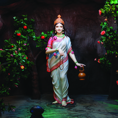 a statue of a woman holding a pot in front of some fruit trees and oranges