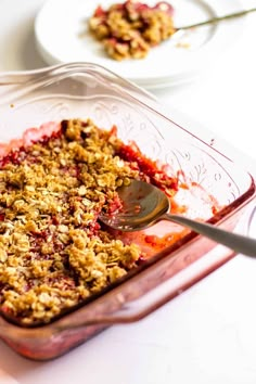 a glass dish filled with crumbled food next to two plates on a table