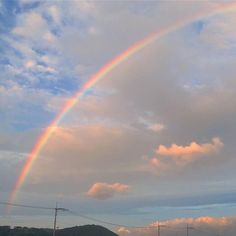 a rainbow in the sky with clouds and power lines