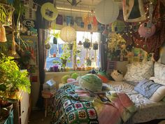 a room filled with lots of potted plants next to a bed covered in blankets