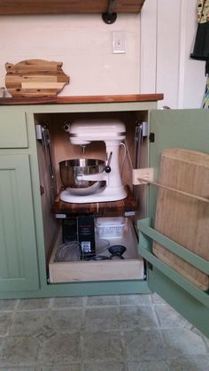 an open kitchen cabinet with a mixer in it