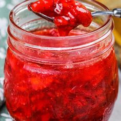 a spoon full of strawberry jam on top of a table