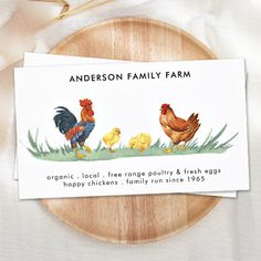 a card with an image of two chickens and one chicken on it, next to a wooden plate