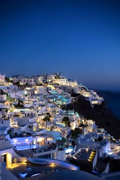 the city is lit up at night by the ocean