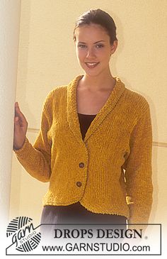 a woman standing in front of a wall wearing a yellow cardigan