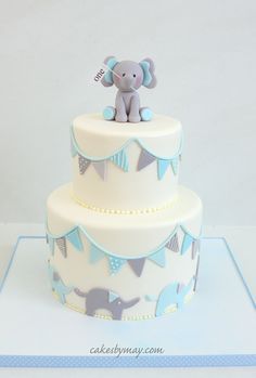 a three tiered cake decorated with an elephant and bunting banner on the top