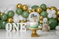 a baby yoda cake sitting on top of a table next to balloons and a star wars sign