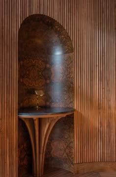 a wooden shelf with a candle on it in front of a wood paneled wall