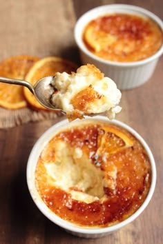 two small bowls filled with food on top of a wooden table next to orange slices