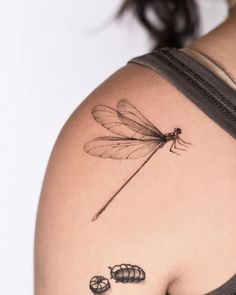 a dragonfly tattoo on the back of a woman's left shoulder and arm