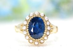 a close up of a ring with a blue stone and pearls on the bottom,