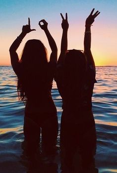 two girls standing in the water with their hands up