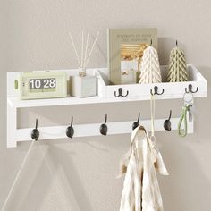 a white shelf with hooks and towels hanging on it