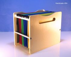 a wooden file cabinet filled with files and folders on top of a white table