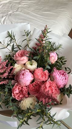 a bouquet of pink and white flowers sitting on top of a bed