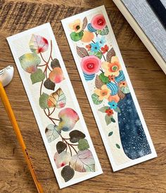 two bookmarks with flowers and leaves painted on them next to a pencil, ruler and an eraser