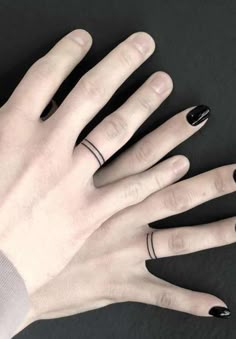 two hands with black and white nail polish on them