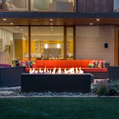 a fire pit sitting in the middle of a yard next to a building with large windows