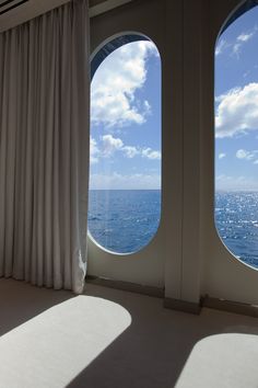 two large windows overlooking the ocean with white curtains