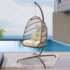 an outdoor swing chair next to a swimming pool with the ocean in the back ground