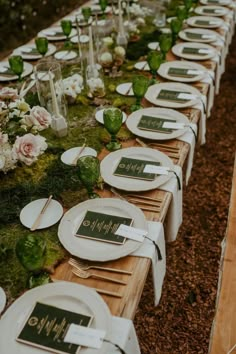 a long table is set with white plates and place settings for the guests to eat