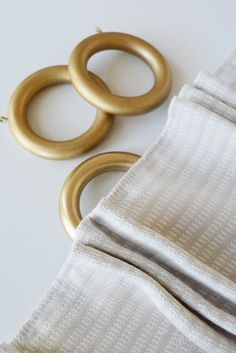 two pairs of gold rings sitting on top of a white table next to a piece of cloth