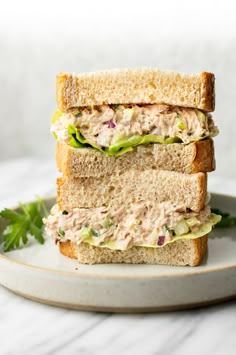 two halves of a sandwich stacked on top of each other with lettuce and tuna