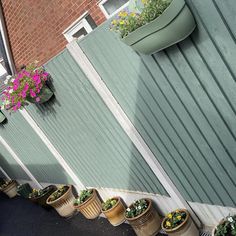 several potted plants on the side of a building next to a wall with flowers in them