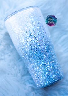 a blue and white glitter tumbler sitting on top of a fur covered floor