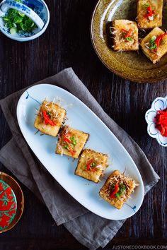 some food is sitting on a white plate next to other plates and bowls with sauces